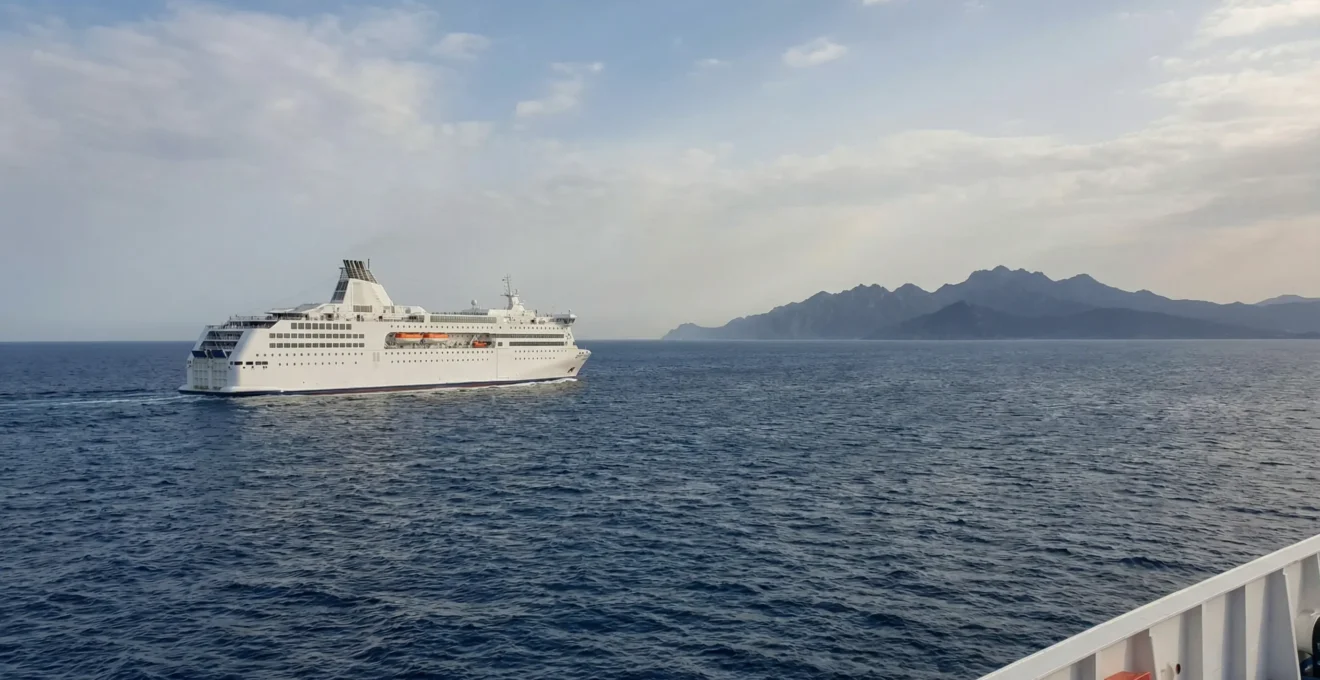 Traghetto in navigazione verso la Corsica nel Mar Tirreno con isola montuosa all'orizzonte